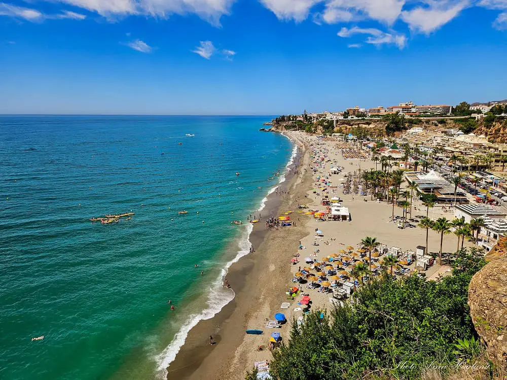 Burriana Beach Nerja which is a stunning Andalucia beach with sunbeds, parasols, and beach bars.