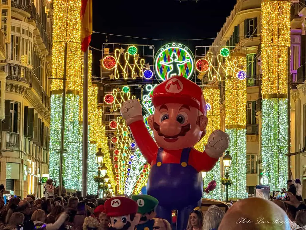 A large figure of Supermario Bros surrounded by lots of people during a parade at Carnival in Malaga Spain.