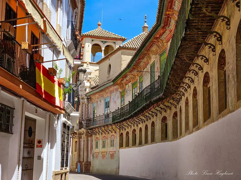 Écija street with a curved building with beautiful frescoes and an old balcony running along the entire wall.