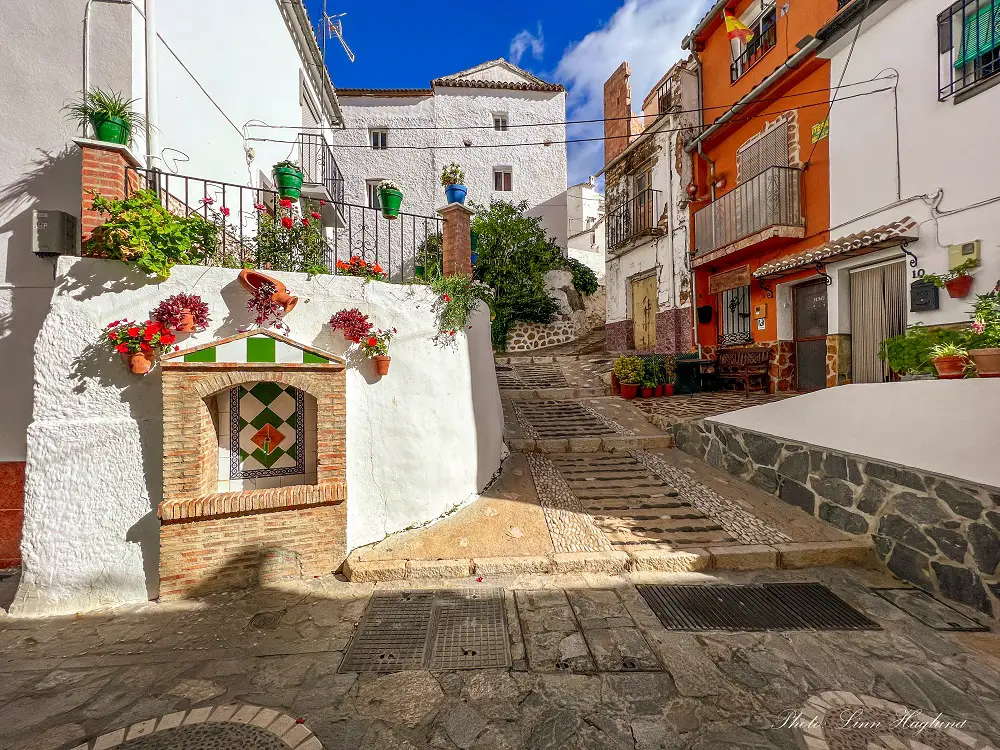 Ronda and white villages - Igualeja village with cobblestoned streets, colorful pot plants on the walls and plants decorating people's doorsteps.