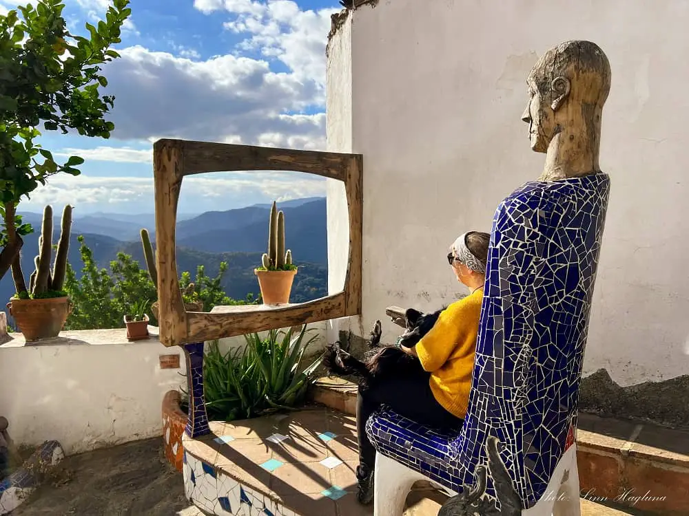 sitting with my dog in a mosaic chair resembling a person looking at the views of the green valley through a piece of art resembling a tv screen