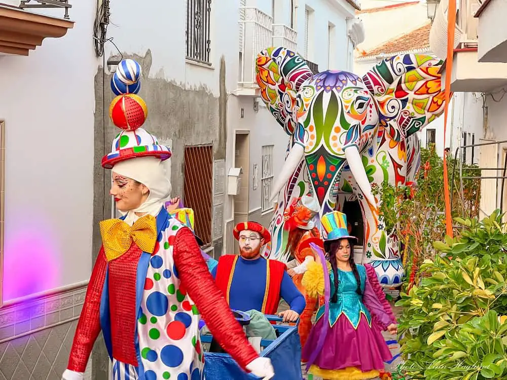 Colorful clowns walking through a narrow street of whitewashed houses in Benalmadena carnival