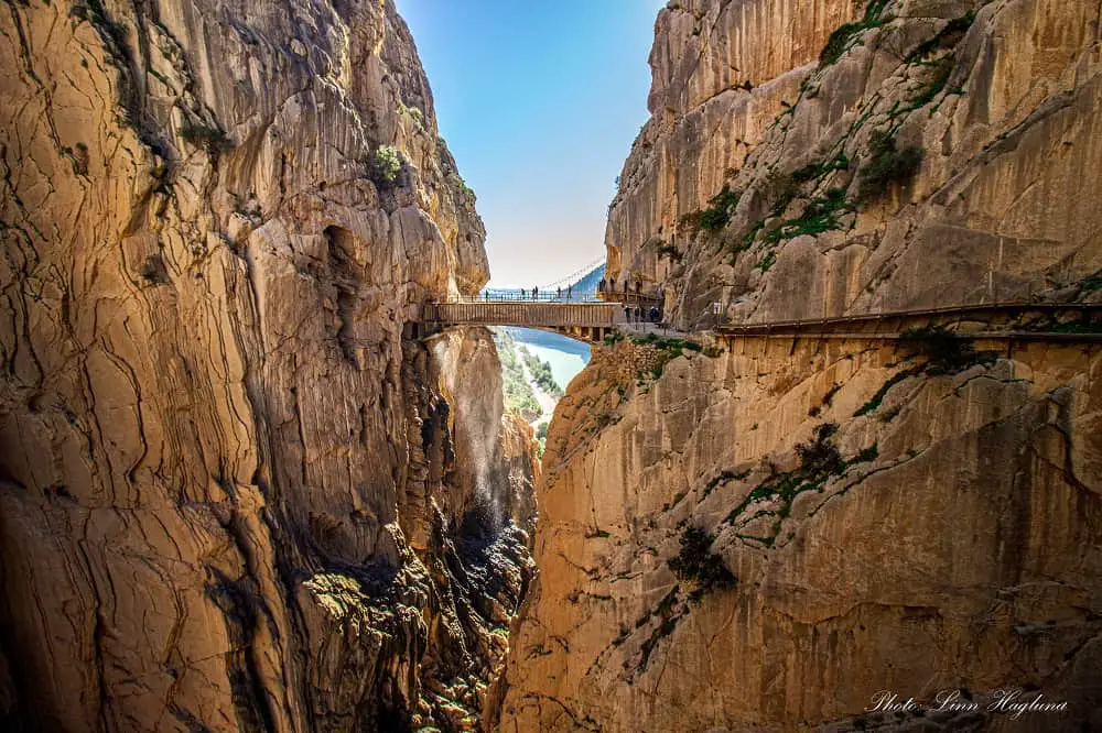 El Caminito del Rey path along a vertical cliff wall with a hanging bridge at the mouth of the gorge.