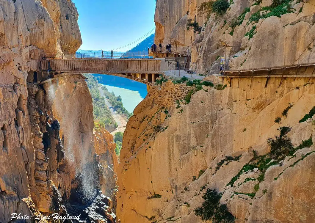 people crossing a hanging bridge in a deep gorge in El Caminito del Rey - best places to visit southern Spain.