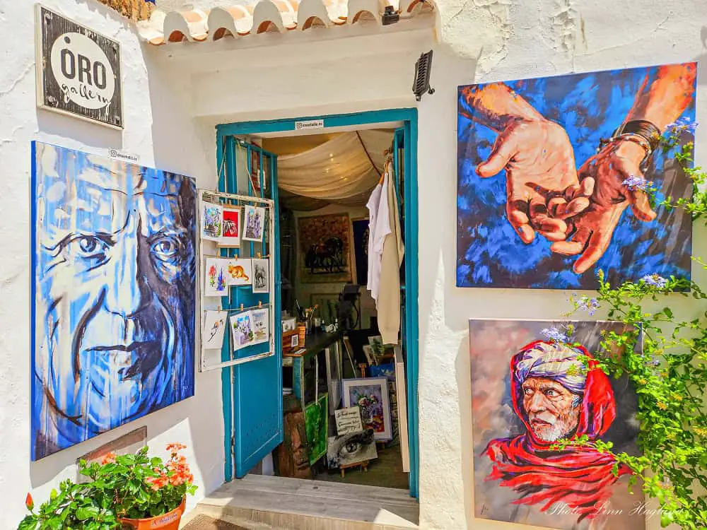 Art shop in Frigiliana with colorful paintings outside of men and hands.