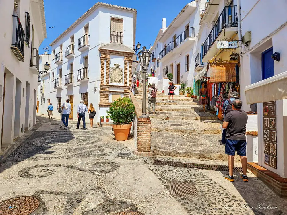 Tourists walking between whitewashed houses which is one of the best things to do in Frigiliana Spain.