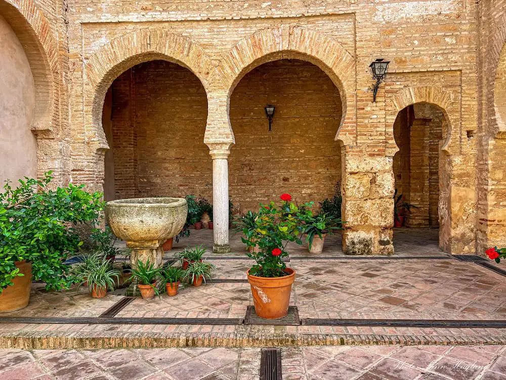 Arab arches and flowers in the patio of Iglesia de Santa Maria de la Granada in Niebla Huelva.