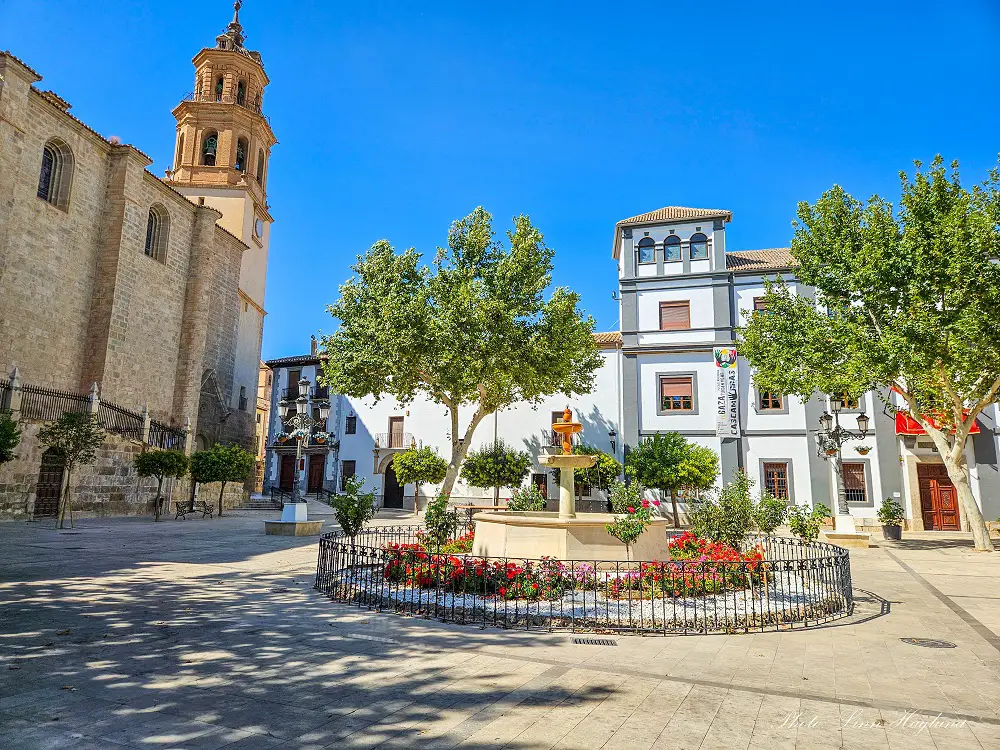 Plaza Mayor de Baza with a central fountain and a church tower overlooking it.
